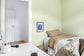 Among the Spirits framed beside a bed in a calm bedroom — room preview only